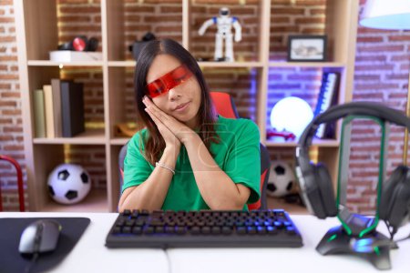 Téléchargez les photos : Moyen-âge femme chinoise portant des lunettes de réalité virtuelle dormir fatigué rêver et posant avec les mains ensemble tout en souriant avec les yeux fermés. - en image libre de droit