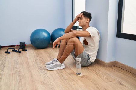 Photo for Young hispanic man tired relaxed sitting on floor at sport center - Royalty Free Image