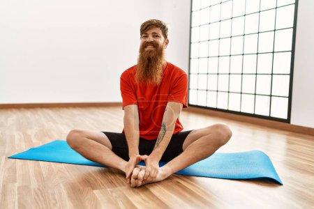 Photo for Young redhead man smiling confident stretching at sport center - Royalty Free Image
