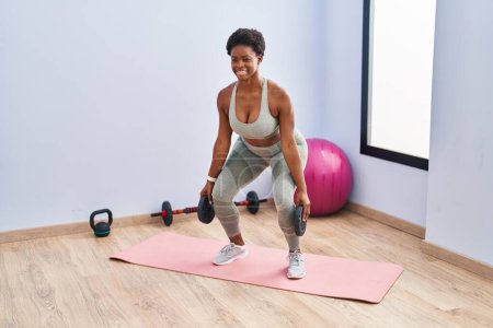 Téléchargez les photos : Femme afro-américaine souriant jambes d'entraînement confiantes exerce au centre sportif - en image libre de droit