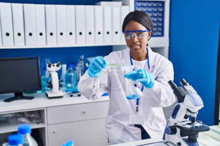 Foto de Joven mujer afroamericana científica midiendo líquido en laboratorio - Imagen libre de derechos