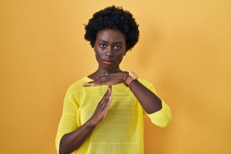 Téléchargez les photos : Jeune femme africaine debout sur le studio jaune faisant un geste avec les mains, le visage frustré et sérieux - en image libre de droit
