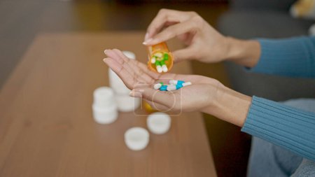 Photo for Young beautiful hispanic woman taking pills at home - Royalty Free Image