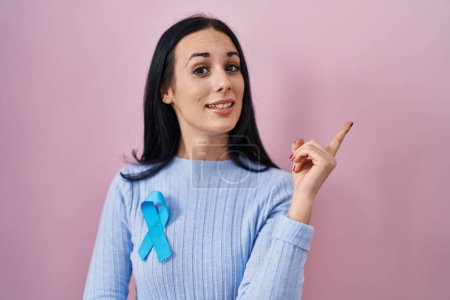 Téléchargez les photos : Femme hispanique portant un ruban bleu souriant heureux pointant avec la main et le doigt sur le côté - en image libre de droit