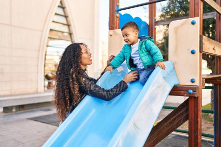Téléchargez les photos : Mother and son playing on slide at park - en image libre de droit