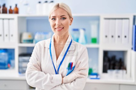 Téléchargez les photos : Young blonde woman wearing scientist uniform standing with arms crossed gesture at laboratory - en image libre de droit
