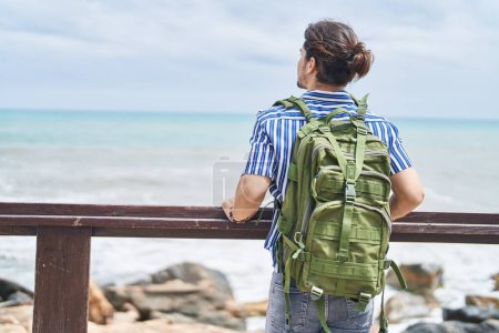Foto de Joven turista hispano con mochila apoyada en balaustrada a orillas del mar - Imagen libre de derechos