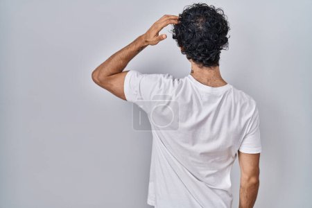 Foto de Hombre hispano parado sobre fondo aislado al revés pensando en la duda con la mano en la cabeza - Imagen libre de derechos