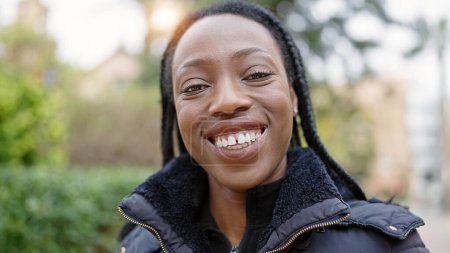 Foto de Mujer afroamericana sonriendo confiada de pie en el parque - Imagen libre de derechos