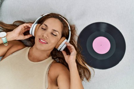 Téléchargez les photos : Jeune femme latine écoutant de la musique allongée sur le canapé à la maison - en image libre de droit