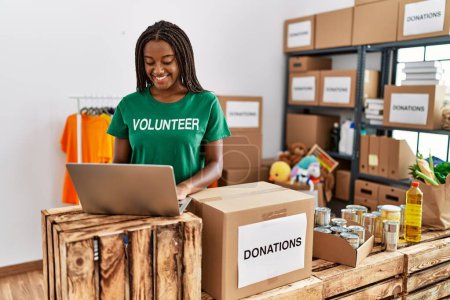 Téléchargez les photos : Jeune femme afro-américaine portant l'uniforme de bénévole travaillant au centre de charité - en image libre de droit
