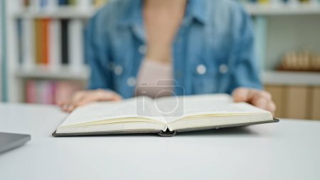Foto de Joven mujer caucásica sentada en la mesa leyendo libro en el aula universitaria - Imagen libre de derechos