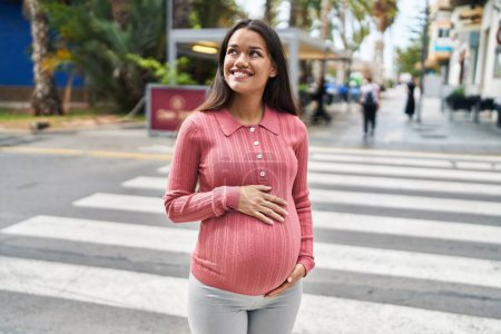 Photo for Young latin woman pregnant smiling confident touching belly at street - Royalty Free Image