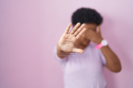 Téléchargez les photos : Jeune femme afro-américaine debout sur fond rose couvrant les yeux des mains et faisant un geste d'arrêt avec expression triste et peur. concept embarrassé et négatif. - en image libre de droit