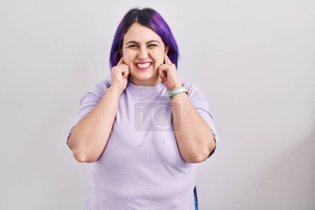 Photo for Plus size woman wit purple hair standing over isolated background covering ears with fingers with annoyed expression for the noise of loud music. deaf concept. - Royalty Free Image
