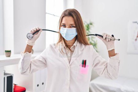 Téléchargez les photos : Jeune femme portant un uniforme de médecin et un masque médical à la clinique - en image libre de droit