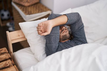 Téléchargez les photos : Jeune homme hispanique stressé couché sur le lit dans la chambre - en image libre de droit