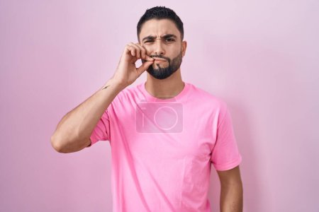 Photo for Hispanic young man standing over pink background mouth and lips shut as zip with fingers. secret and silent, taboo talking - Royalty Free Image