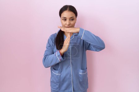 Photo for Young arab woman wearing blue pajama doing time out gesture with hands, frustrated and serious face - Royalty Free Image