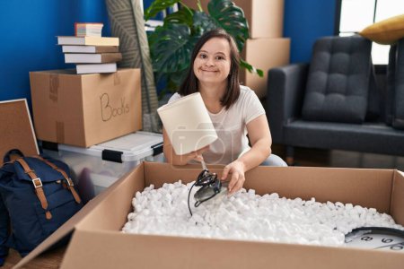 Photo for Down syndrome woman smiling confident unboxing package at new home - Royalty Free Image
