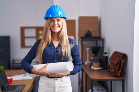 Photo for Young woman wearing architect hardhat looking positive and happy standing and smiling with a confident smile showing teeth - Royalty Free Image