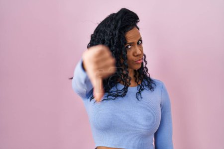 Photo for Middle age hispanic woman standing over pink background looking unhappy and angry showing rejection and negative with thumbs down gesture. bad expression. - Royalty Free Image