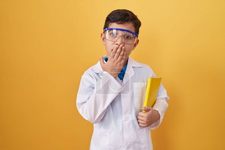 Téléchargez les photos : Petit garçon hispanique portant des lunettes de scientifique couvrant la bouche avec la main, choqué et effrayé par l'erreur. expression surprise - en image libre de droit