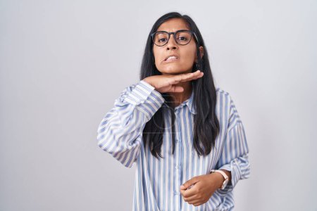 Téléchargez les photos : Jeune femme hispanique portant des lunettes tranchant la gorge avec la main comme couteau, menace d'agression avec une violence furieuse - en image libre de droit