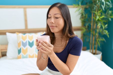 Photo for Young asian woman drinking cup of coffee sitting on bed at bedroom - Royalty Free Image