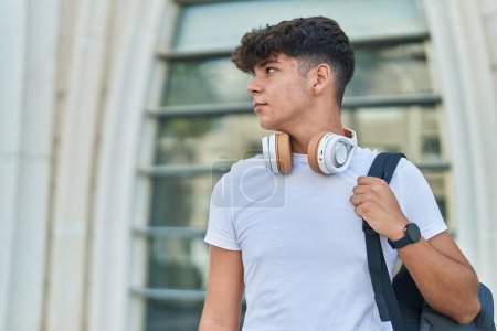 Téléchargez les photos : Jeune adolescent hispanique portant un sac à dos avec une expression détendue à l'université - en image libre de droit