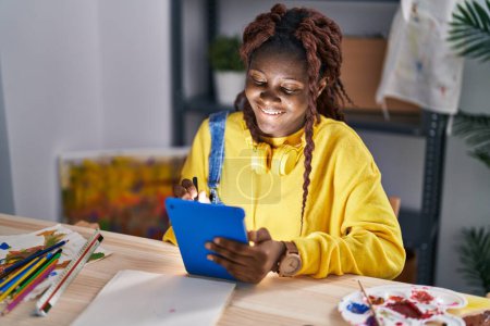 Téléchargez les photos : Femme artiste afro-américaine souriant dessin confiant sur pavé tactile au studio d'art - en image libre de droit