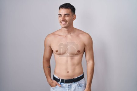 Foto de Hombre hispano guapo de pie guiño sin camisa mirando a la cámara con expresión sexy, cara alegre y feliz. - Imagen libre de derechos