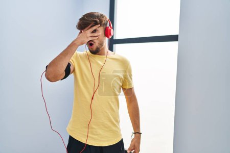 Photo for Arab man with beard wearing sportswear and headphones relaxed with serious expression on face. simple and natural looking at the camera. - Royalty Free Image