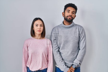 Foto de Young hispanic couple standing together relaxed with serious expression on face. simple and natural looking at the camera. - Imagen libre de derechos