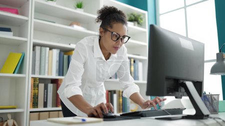Téléchargez les photos : African american woman student using computer studying at library university - en image libre de droit