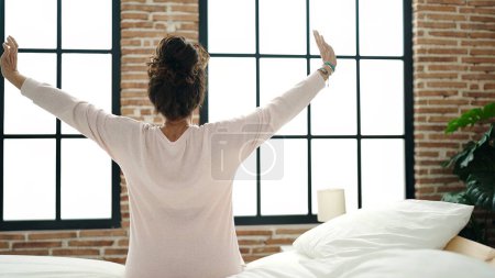 Photo for Middle age hispanic woman waking up stretching arms at bedroom - Royalty Free Image