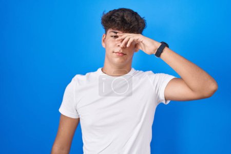 Photo for Hispanic teenager standing over blue background worried and stressed about a problem with hand on forehead, nervous and anxious for crisis - Royalty Free Image