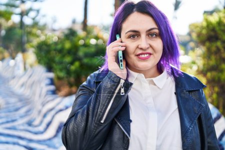Téléchargez les photos : Jeune belle plus taille femme souriant confiant parler sur le smartphone au parc - en image libre de droit