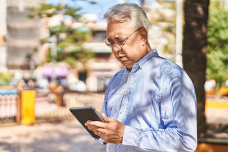 Téléchargez les photos : Senior man using touchpad at park - en image libre de droit