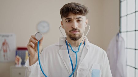 Téléchargez les photos : Jeune homme arabe médecin tenant stéthoscope à la clinique - en image libre de droit