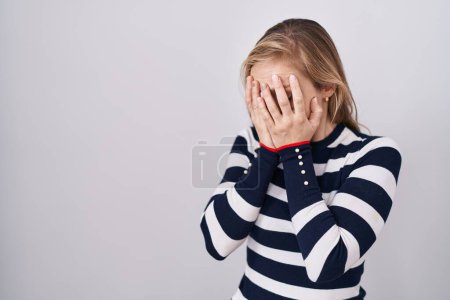 Foto de Mujer caucásica joven que usa suéter azul marino casual con expresión triste que cubre la cara con las manos mientras llora. concepto de depresión. - Imagen libre de derechos