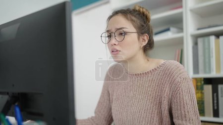 Téléchargez les photos : Young beautiful hispanic woman student using computer studying at library university - en image libre de droit