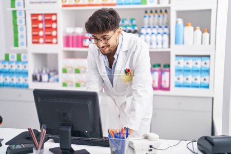 Photo for Young arab man pharmacist using computer working at pharmacy - Royalty Free Image