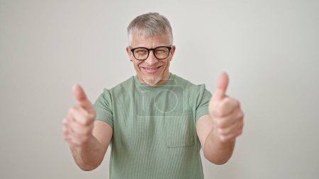 Foto de Hombre de pelo gris de mediana edad sonriendo con pulgares hacia arriba sobre un fondo blanco aislado - Imagen libre de derechos