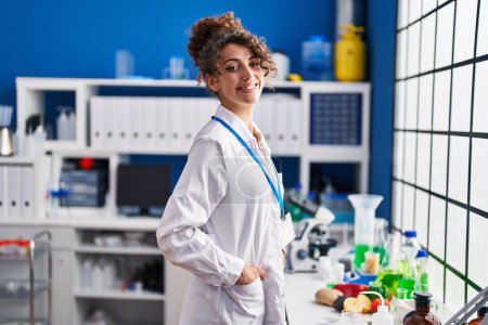 Téléchargez les photos : Jeune femme hispanique scientifique souriant confiance debout au laboratoire - en image libre de droit