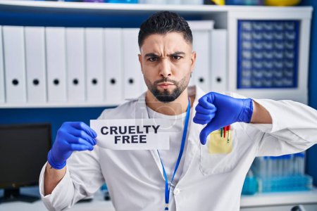 Photo for Young handsome man working at scientist laboratory holding cruelty free banner with angry face, negative sign showing dislike with thumbs down, rejection concept - Royalty Free Image