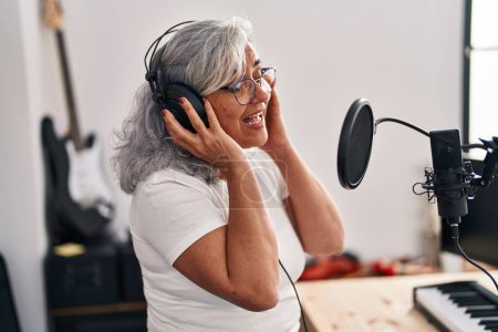 Foto de Mujer de mediana edad músico cantando canción en el estudio de música - Imagen libre de derechos