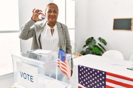 Photo for Senior african american woman holding i voted badge voting at electoral college - Royalty Free Image