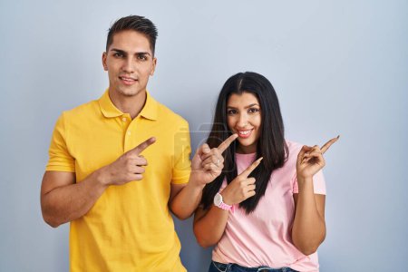 Téléchargez les photos : Jeune couple debout sur fond isolé souriant et regardant la caméra pointant avec deux mains et doigts sur le côté. - en image libre de droit