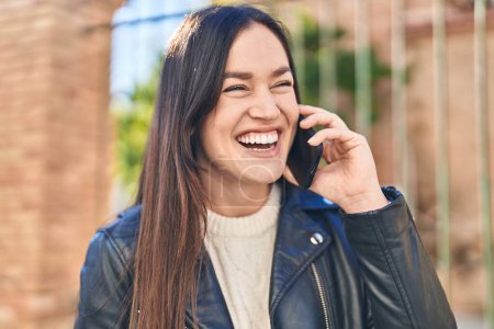 Foto de Mujer joven sonriendo confiada hablando en el teléfono inteligente en la calle - Imagen libre de derechos
